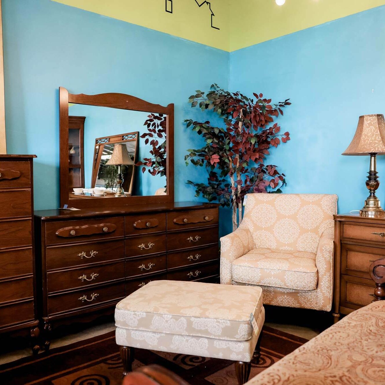 Photo of a corner of the ReStore, it is arranged with for sale furniture setup like a cozy living room with stately dark wood furniture